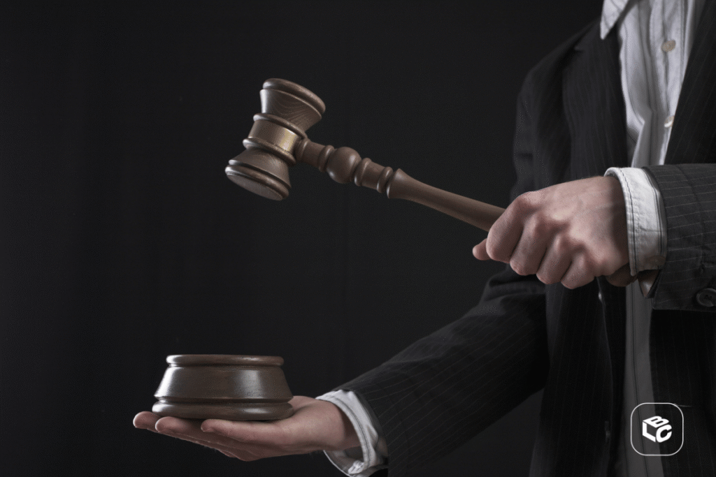Mão de pessoa de terno com um martelo da justiça na mão
