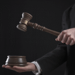 Mão de pessoa de terno com um martelo da justiça na mão